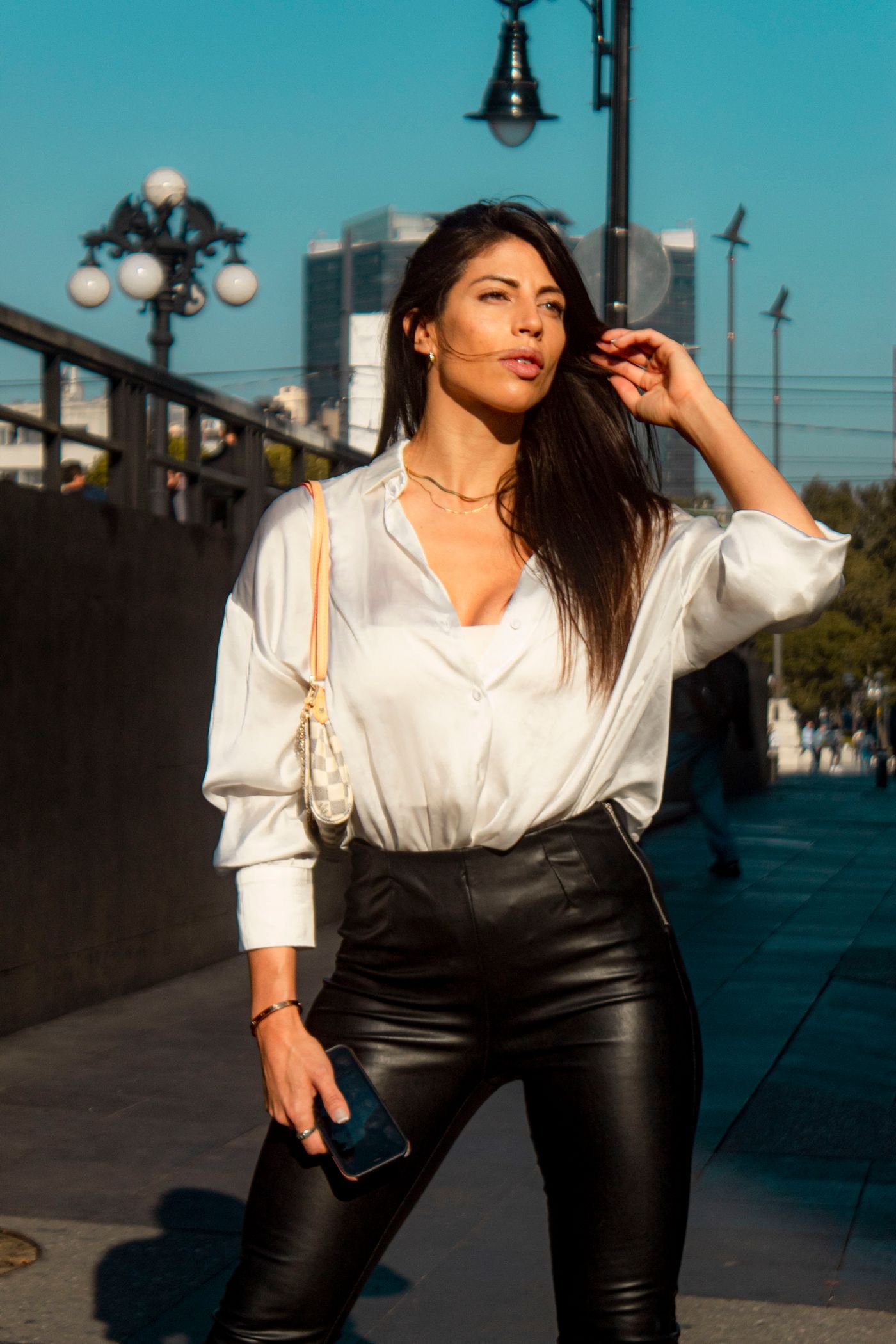 Woman wearing leather pants and a white blouse walking in the city